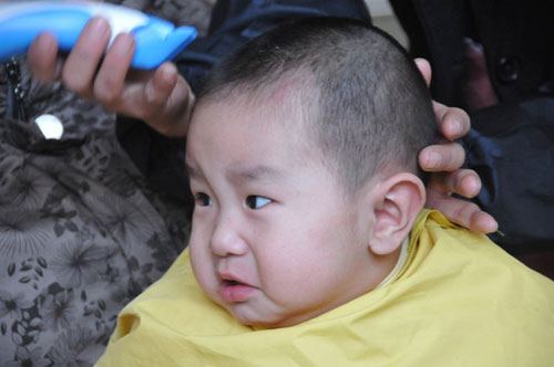 A child gets a haircut at a barbershop in Hefei